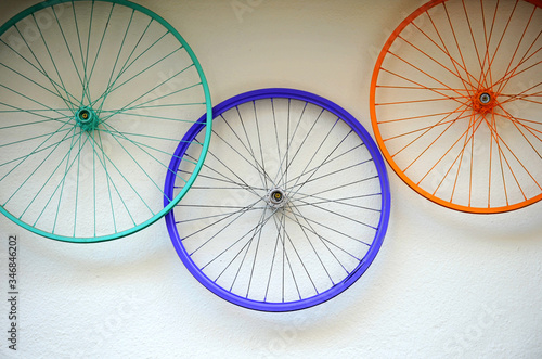 Old bicycle wheels colorful on the wall of a rental and repair shop, hipster decorative trend concept