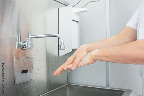 Doctor washes his hands according to all the rules before starting the procedure close up