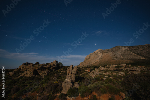 Night mountains view with star sky and full moon of the The petrified forest park in Lakonia, Peloponnese, Greece. View of petrified forest with plant fossils on star sky background.