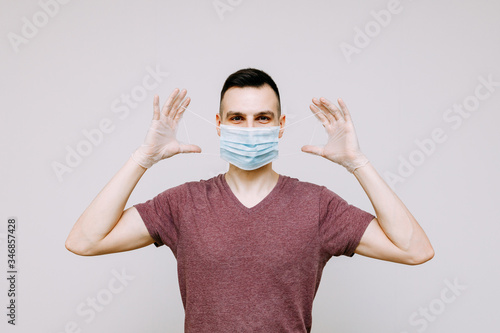 A man on a white background puts on or removes a hygiene mask to prevent infection with flu, colds, or coronavirus.