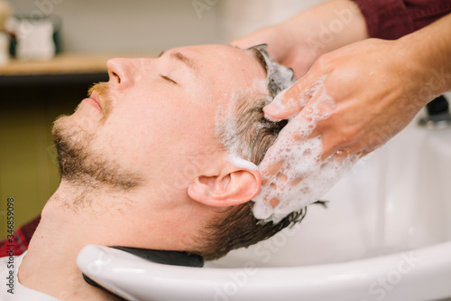 Side view of man washing hair at barber shop