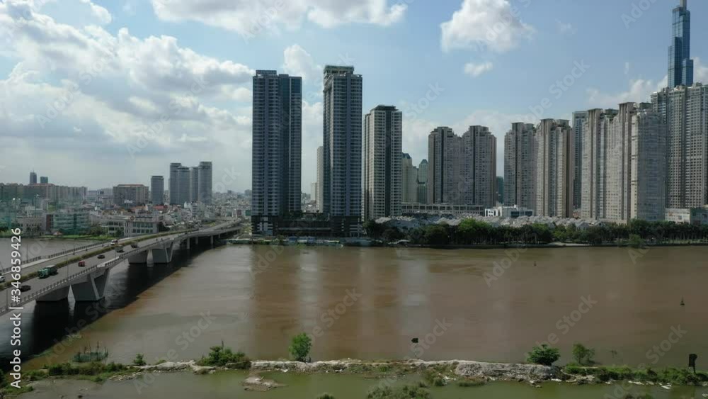 Saigon River showing a long thin island near the riverbank and the Ho Chi Minh City Skyline on sunny day featuring roads, bridge, high rise and low rise architecture. Saigon River showing a long thin island near the riverbank and the Ho Chi Minh City Skyline on sunny day featuring roads, bridge, high rise and low rise architecture.