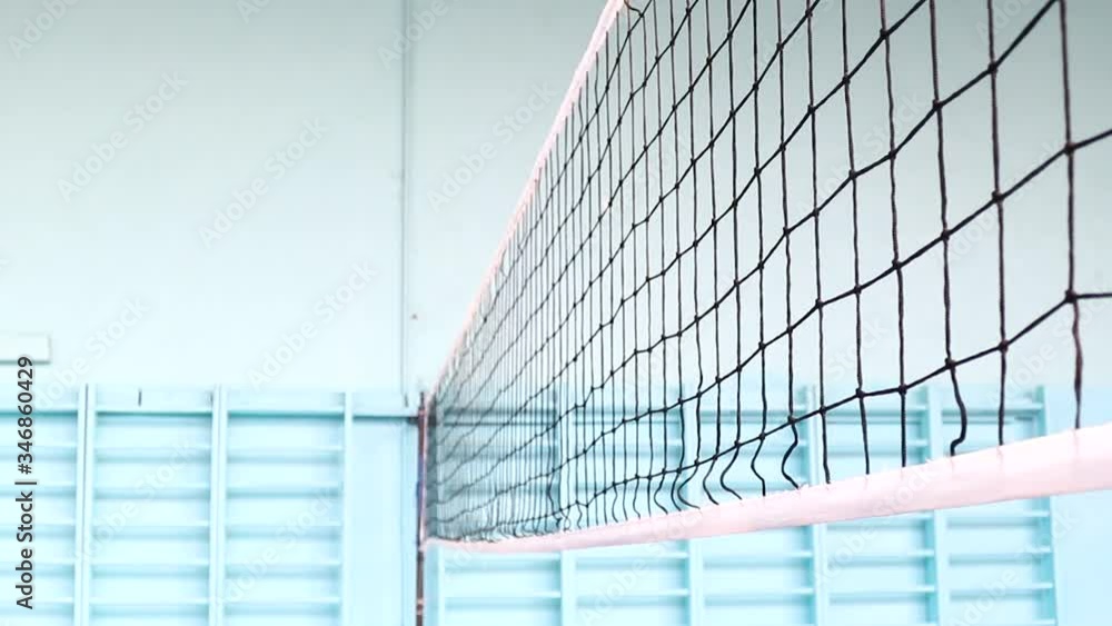 Volleyball competition in the gym, players do a warm-up before the match, flying balls over the volleyball net. The ball hit the net, video before the tournament, sports games with the ball Volleyball competition in the gym, players do a warm-up before the match, flying balls over the volleyball net. The ball hit the net, video before the tournament, sports games with the ball