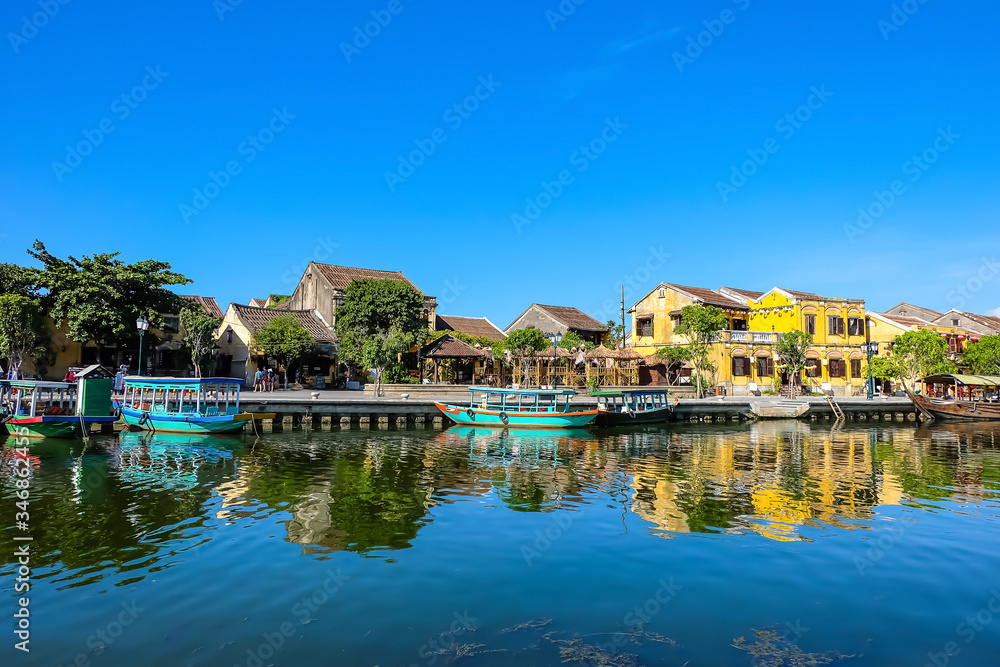 Hoi An ancient town in the sunshine day with blue sky, fishing boats, ancient houses reflect on the river. Hoi An is a popular tourist destination in Quang Nam, Vietnam. Landscape photography.