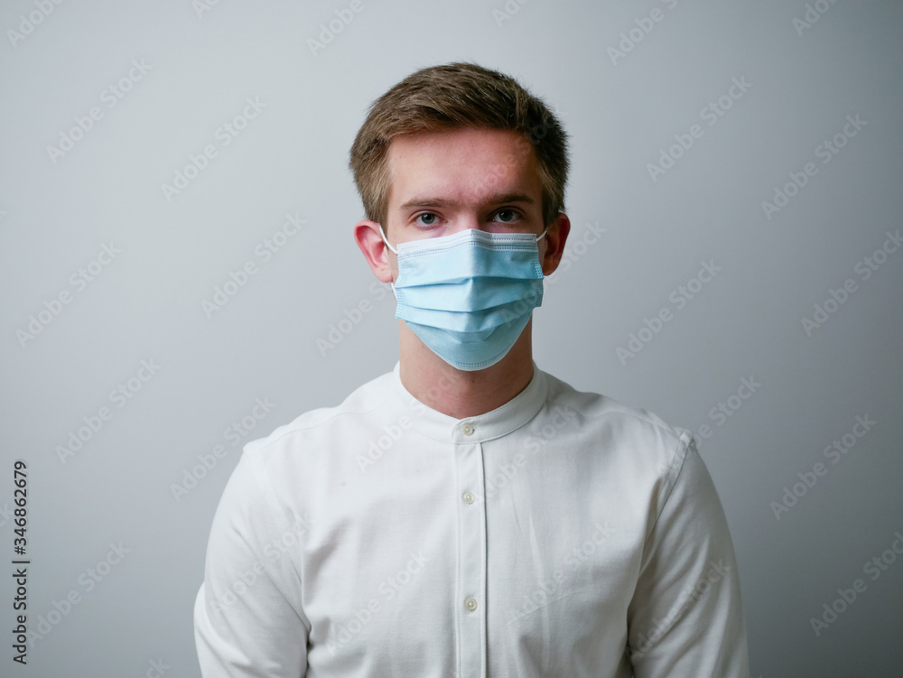 Man wearing a blue protective face mask against coronavirus. Medical staff preventive gear. White background. Man wearing a blue protective face mask against coronavirus. Medical staff preventive gear. White background.