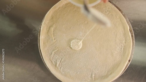chef puts cheese sauce on the pizza dough