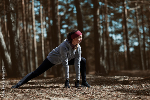 Girl does warm-up before exercising. Running in the pine forest.