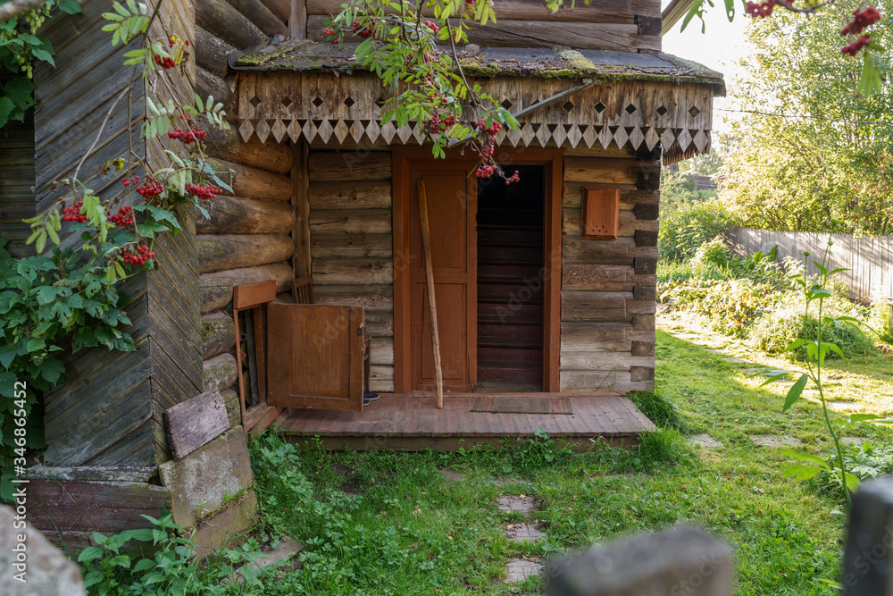 old russian wooden house with opened door and yard
