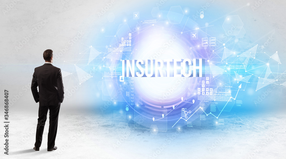 Fototapeta premium Rear view of a businessman standing in front of INSURTECH inscription, modern technology concept