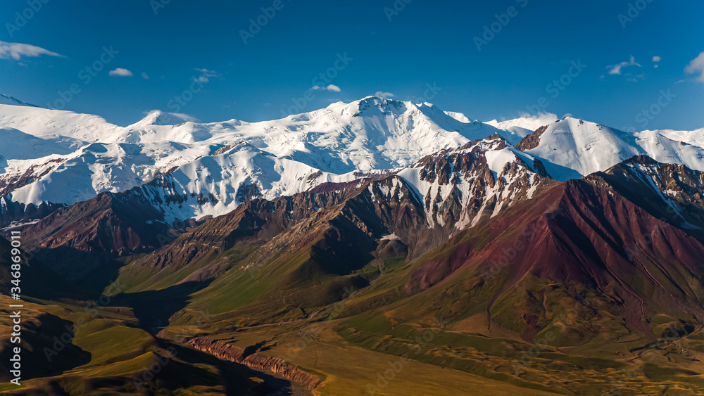 Beautiful mountainious landscape. Snowy mountain peaks. Hilly valley.