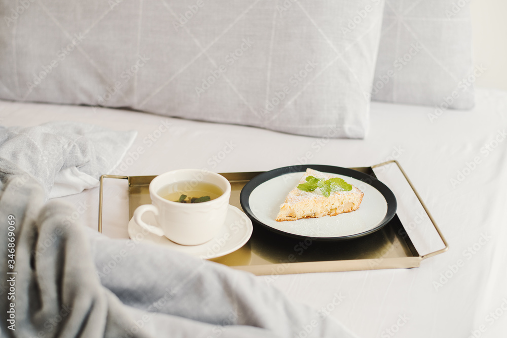Breakfast in bed: mint tea and a piece of apple pie served on a metal tray Breakfast in bed: mint tea and a piece of apple pie served on a metal tray