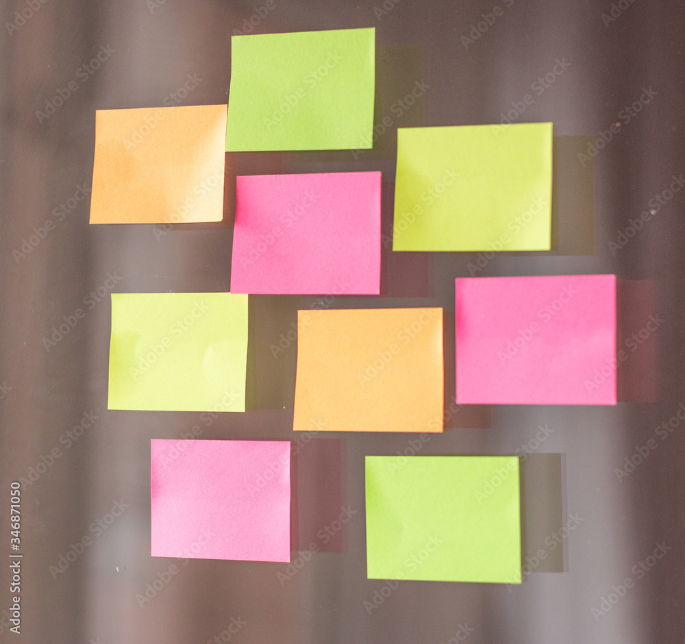 Close-up of sticky multicolored notes on a glass wall in the office. Horizontal photo. Close-up of sticky multicolored notes on a glass wall in the office. Horizontal photo.