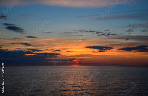 Sun is setting behind the Baltic Sea. The sky is colorful combination of yellows, oranges and blues. The photo is a dramatic because of the big clouds, and sea with waves. Very scenic. © Dmytro