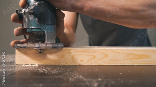 Worker bevel wooden board. Milling cutter and sawdust, closeup. Professional carpentry concept.