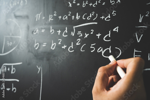 Education background concept. Close up male hand writing mathematical formula on chalkboard. © Chanakon
