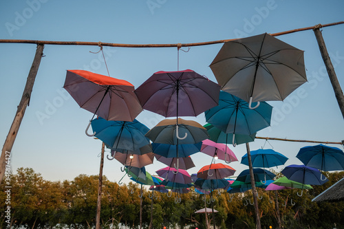 Group of colorful umbrellas hanging on a rope isolated from blue sky background. colored umbrellas isolated from bright sky background.