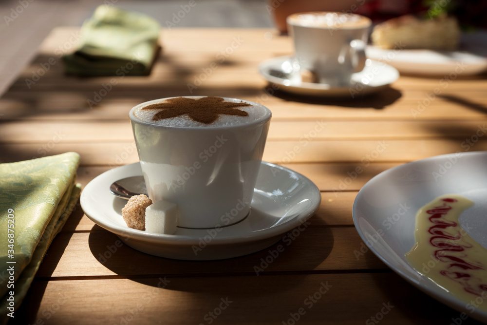 two cups of coffee on a wooden table in an outdoor cafe