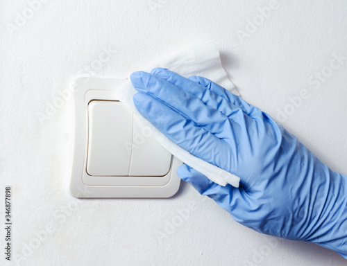 Woman with surgical gloves wiping and cleaning .  light bulb switcher . Bacteria   and covid-19    virus spreading  prevention  .