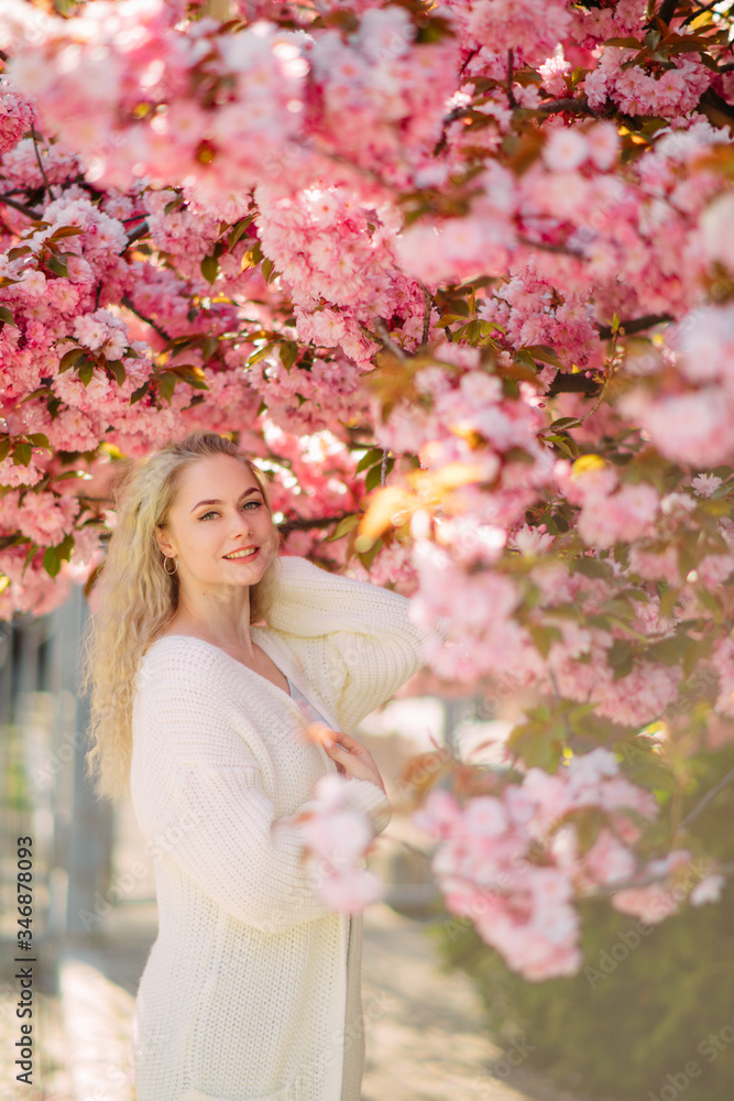 Woman walks in park with blooming sakura trees Woman walks in park with blooming sakura trees