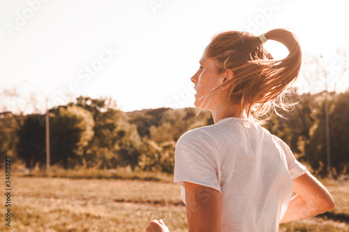 Profilo di giovane ragazza che corre nel parco urbano facendo jogging in solitudine con concentrazione e determinazione photo