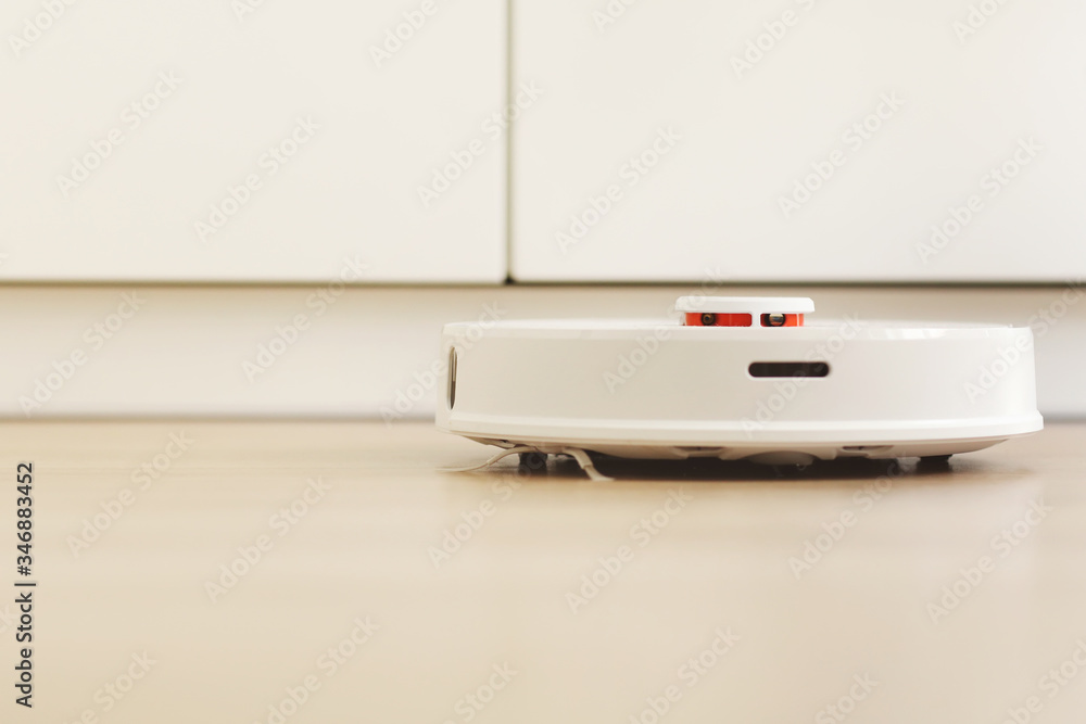 white robotic vacuum cleaner. The robot is controlled by voice commands for direct cleaning. Modern technology of smart cleaning. scheduled cleaning of the apartment. selective focus white robotic vacuum cleaner. The robot is controlled by voice commands for direct cleaning. Modern technology of smart cleaning. scheduled cleaning of the apartment. selective focus
