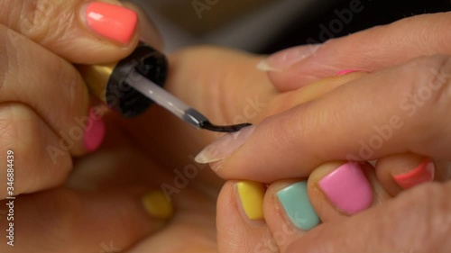 Painting nails with hybrid varnish in a beauty salon. Pink and purple nail polish