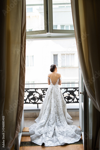 The bride stands on the balcony and looks at the street.