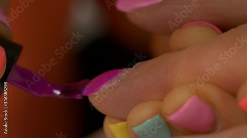 Painting nails with hybrid varnish in a beauty salon. Pink and purple nail polish