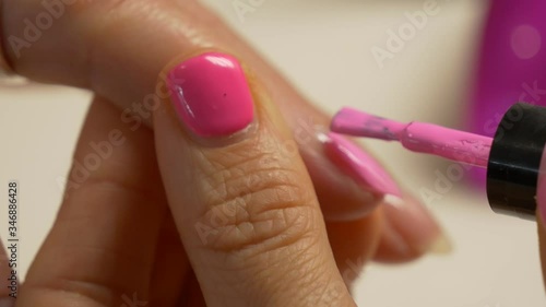 Painting nails with hybrid varnish in a beauty salon. Pink and purple nail polish