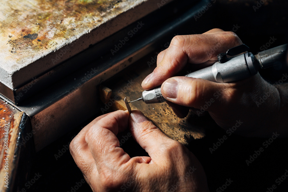 Fototapeta premium The hands of a goldsmith working the silver in his craftsman's workshop.