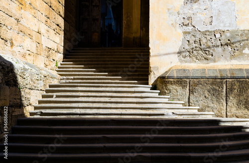 City detail of the beautiful mediterranean Salerno in South Italy. A beautyful ancient stairway defined by the contrast of the sun light and its shadows leads to the secondary entrance of the church