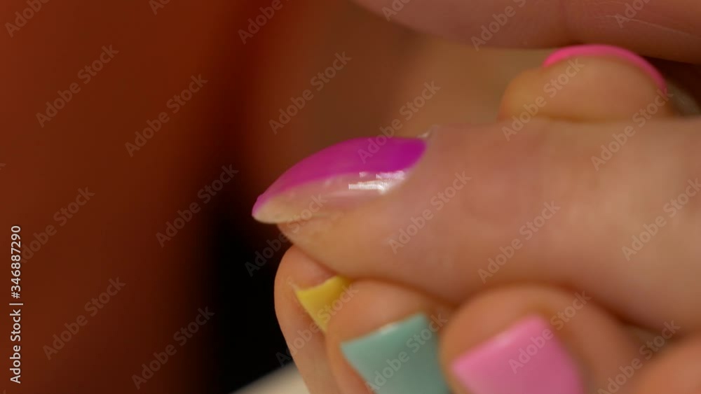 Painting nails with hybrid varnish in a beauty salon. Pink and purple nail polish Painting nails with hybrid varnish in a beauty salon. Pink and purple nail polish