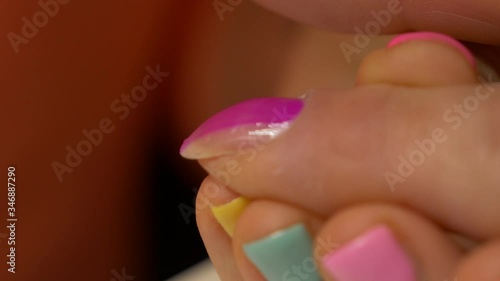 Painting nails with hybrid varnish in a beauty salon. Pink and purple nail polish