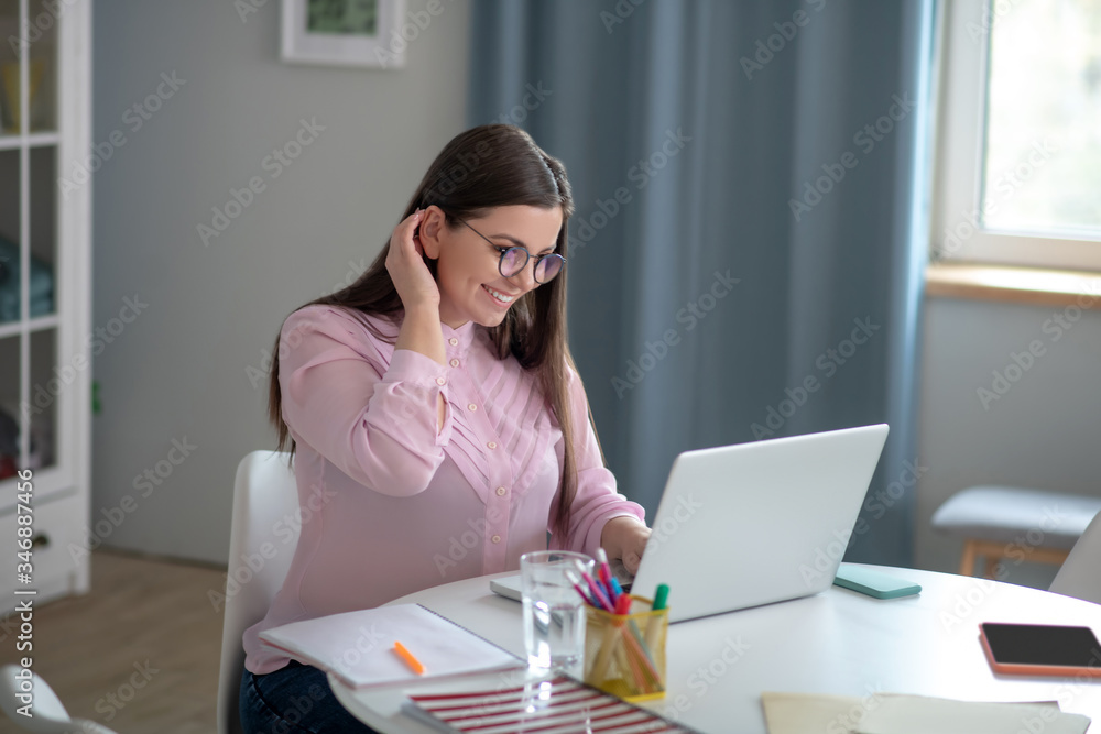 Woman in a pink blouse wearing eyeglasses having a video conference Woman in a pink blouse wearing eyeglasses having a video conference