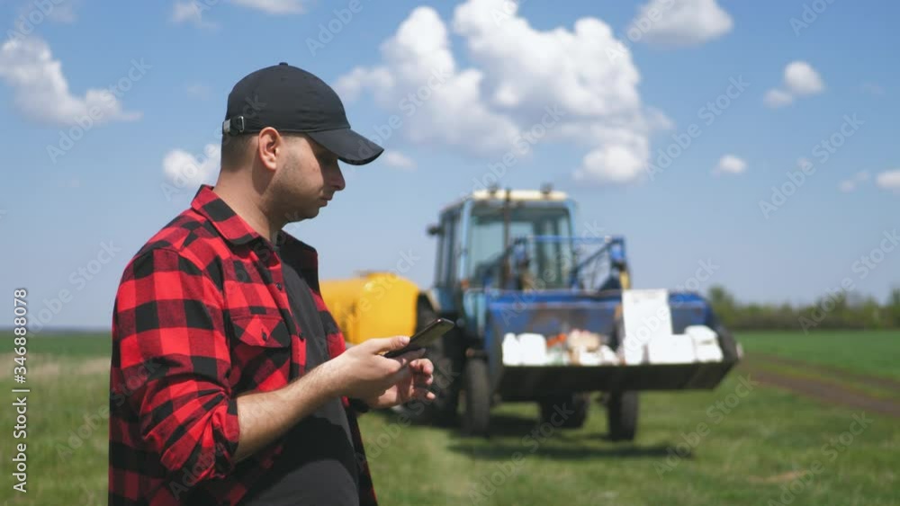 A pensive farmer is working in the field. Uses a tablet, stands near the agricultural engineering. A pensive farmer is working in the field. Uses a tablet, stands near the agricultural engineering.