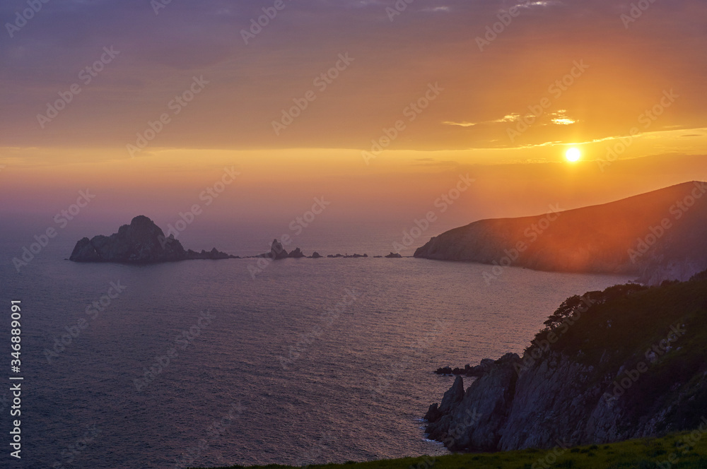 Rocky islands and peninsulas in the ocean at sunset.