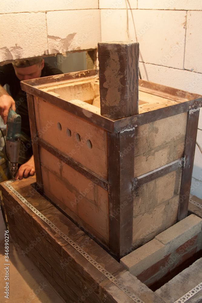 Sauna stove that is being built from fire resistant material in undeveloped interior laid out of foam blocks in country house under construction
