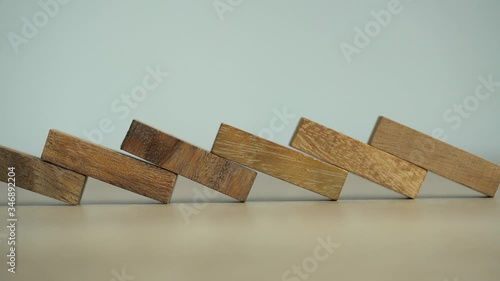 Business risks concept. Hand push wooden brick with domino effect.