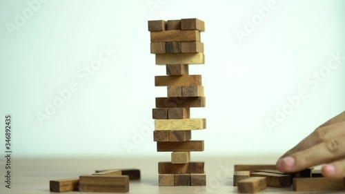 Business risks concept. Hand pulls out wooden brick with jenga game. jenga falls