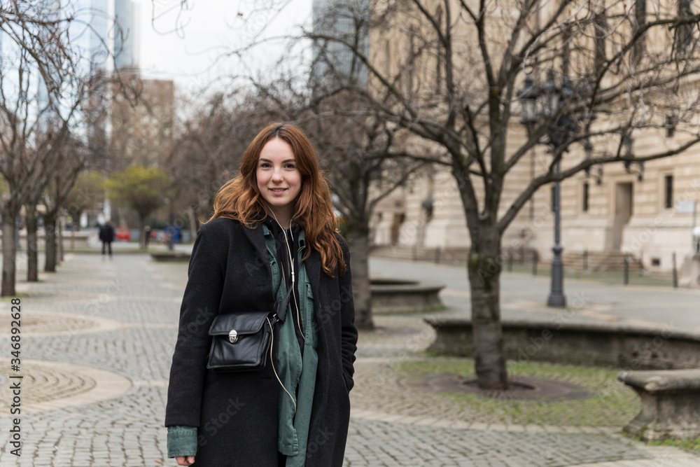 Fototapeta premium Young Caucasian Woman Smiling at Camera in Pedestrian Zone
