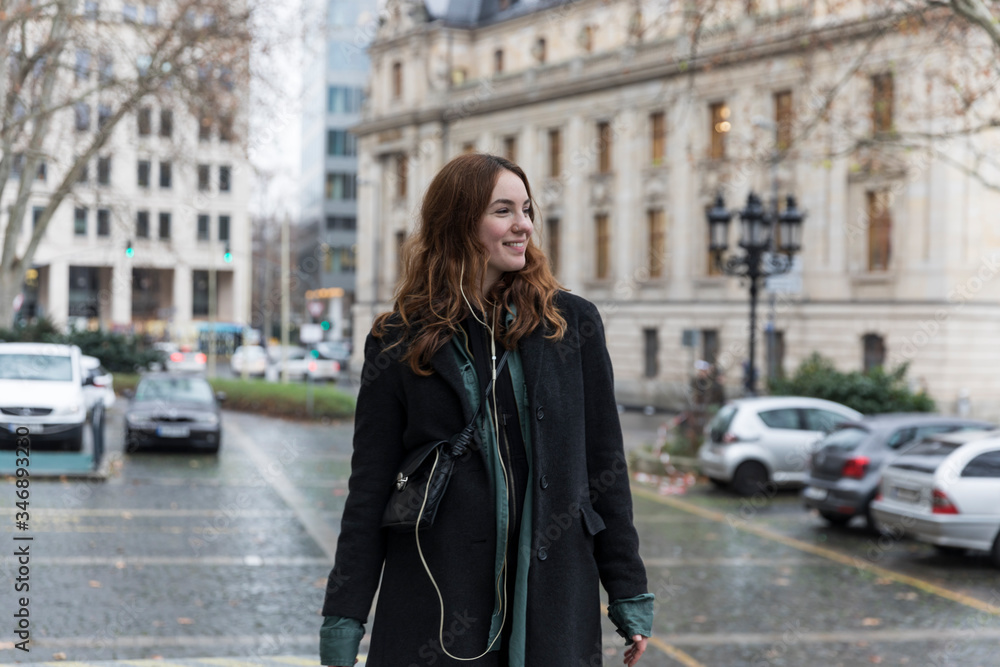 Fototapeta premium Young Urbanite Woman with Genuine Smile Looking Away in City
