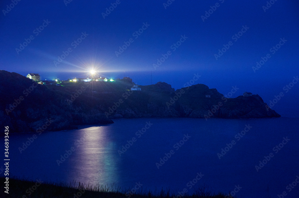 Fototapeta premium Old lighthouse at night. Light of a lighthouse. Gamow Lighthouse on the Gamow Peninsula. Dangerous Bay in the Sea of Japan. Far East. Light of a lighthouse at night on the peninsula.