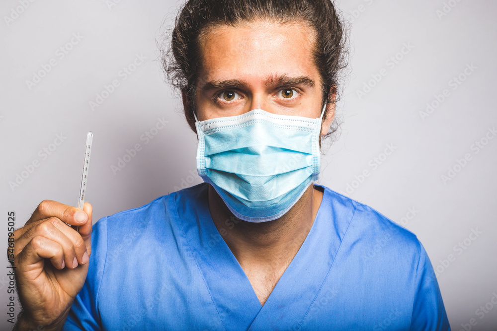 young adult wearing a medic mask and medic uniform showing a thermometer
young adult wearing a medic mask and medic uniform showing a thermometer
