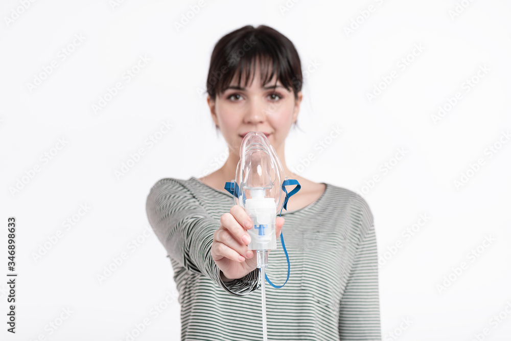 smiling brunette woman holding inhalation mask in front of her face. pulmonary diseases recovery treatment concept