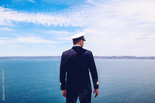 Strong posture of a captain looking at the sea and faraway land on the horizon. Navy/Cruise ship concept. Outdoor shot. photo
