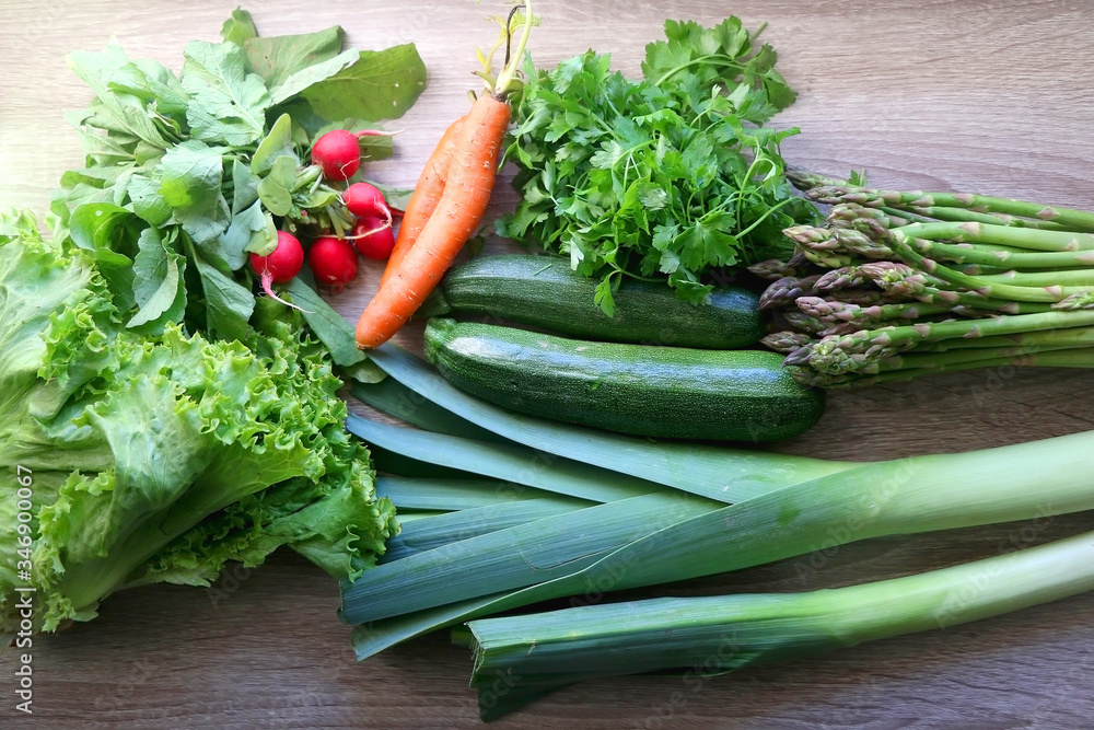 Various vegetables and herbs on a table: leek, lettuce, asparagus, parsley, carrot and radish. Top view. Various vegetables and herbs on a table: leek, lettuce, asparagus, parsley, carrot and radish. Top view.