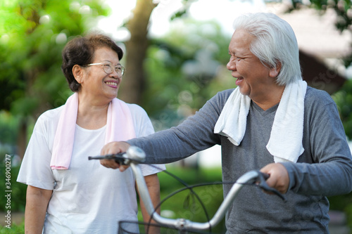  A senior couple is happily riding their bicycles in the park in the morning. © panyawat