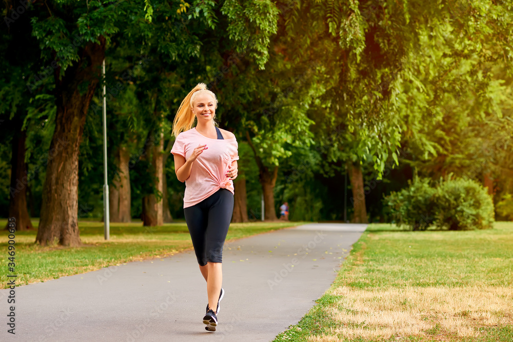Young woman running on the road in a park