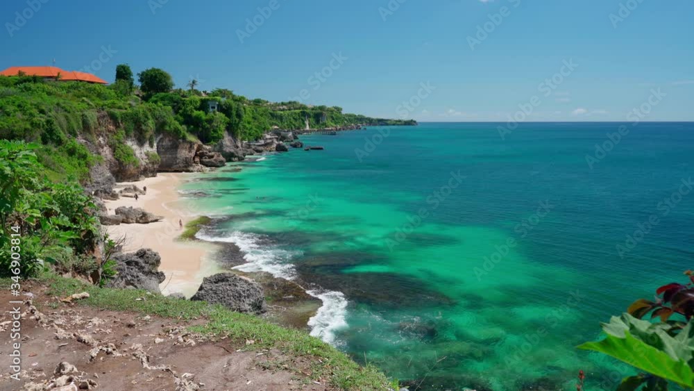 Sandy beach with rocky mountains and clear water of Indian ocean at sunny day. Bali, Indonesia. 4K Sandy beach with rocky mountains and clear water of Indian ocean at sunny day. Bali, Indonesia. 4K