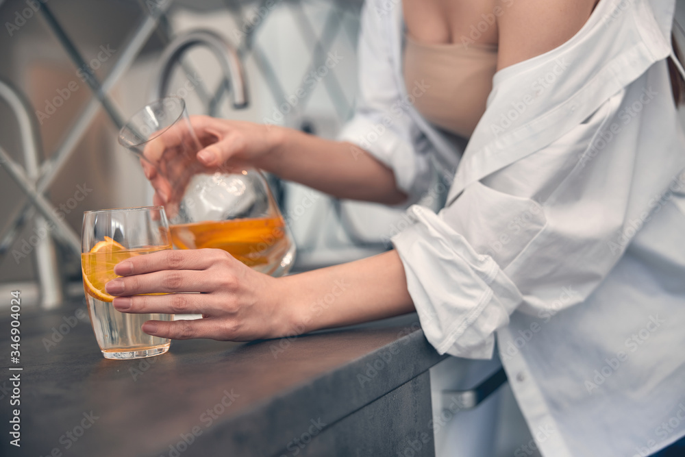 Caucasian woman pouring lemonade in glass at home Caucasian woman pouring lemonade in glass at home